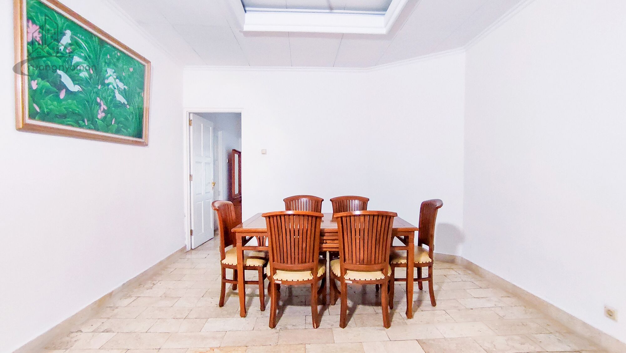 Un comedor con una mesa, sillas, un cuadro en la pared y un tragaluz.