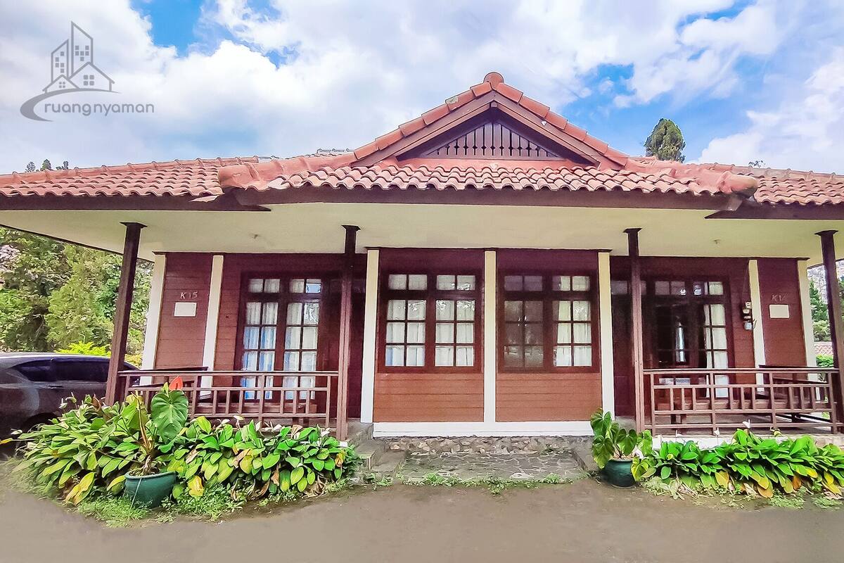 A traditional house with a tiled roof, two front doors, and a porch with railings.