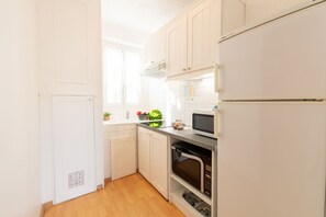 A compact kitchen with white cabinets, a microwave, and a built-in oven.