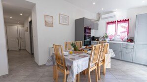 Une cuisine moderne avec un coin repas, où une table est dressée pour le petit-déjeuner avec des fruits et des boissons.