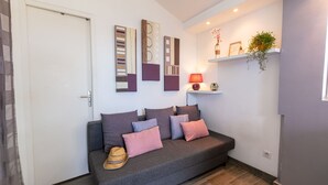 A modern living room with a grey sofa, multiple cushions, a decorative hat, and wall art.