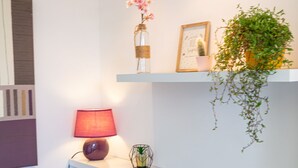 A modern living room with a sofa, pillows, a lamp, and decorative items on shelves.