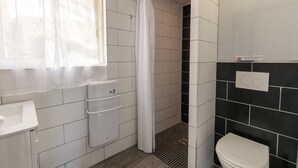 A bathroom with a toilet, a sink, a shower with a curtain, and tiled walls.