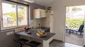 A modern kitchen with a central island, a dining area with a table and chairs, and a view of the outdoors.