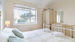 Quarto com cama, janela, abajur, cômoda e espelho.