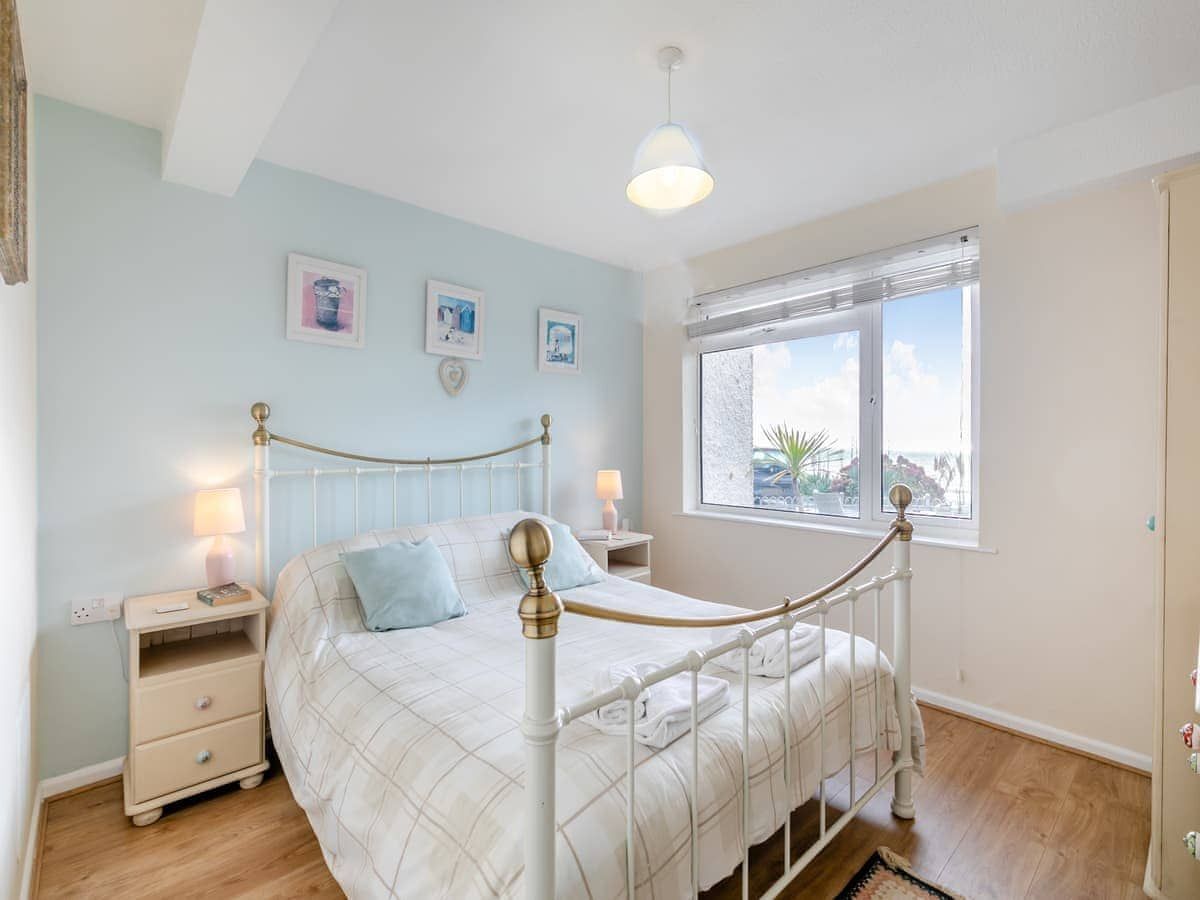A bedroom with a bed, bedside tables, a window, and a view of the outside.