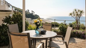 A patio with a table and chairs overlooking a beach. - Amazing Sea Views from this Ground Floor 2 Bedroom High Spec Apartment (Torpoint)