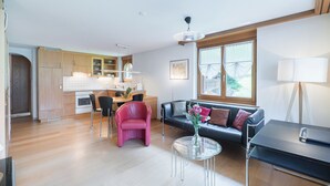 A modern living room with a black leather sofa, a pink armchair, and a glass coffee table. - Haus Bärgbach by Zermatt Premium Apartments (Zermatt)