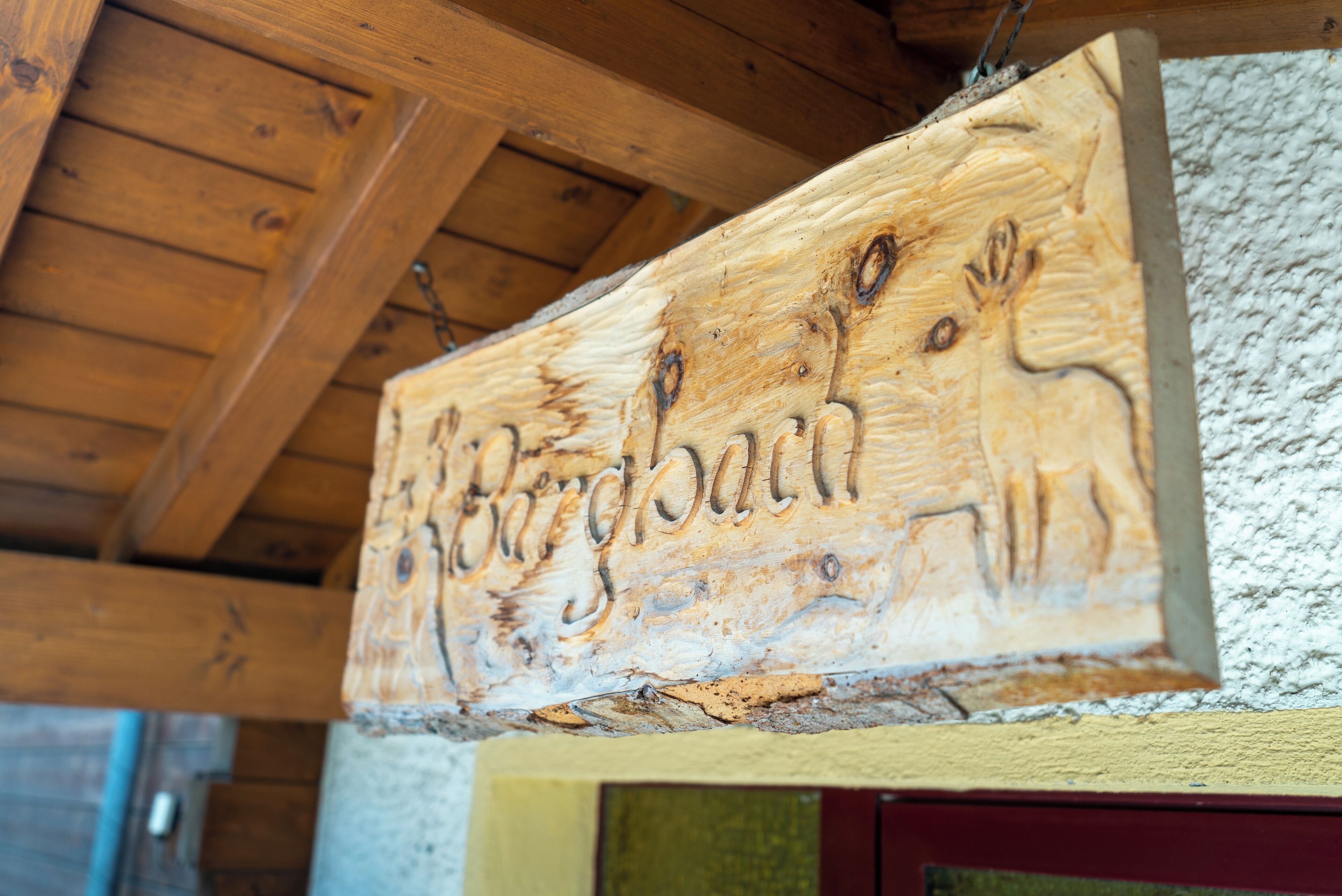 Een houten bord met houtsnijfiguren, waarschijnlijk om een lokale bezienswaardigheid of herkenningspunt aan te duiden.
