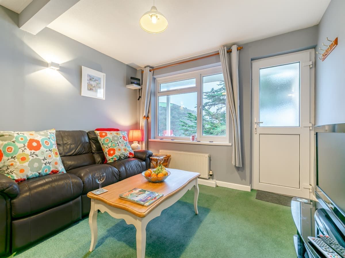 Ein gemütliches Wohnzimmer mit einer Ledersofa, einem Holztisch und einem großen Fenster mit Vorhängen.