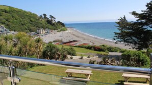 A beach with a view of the ocean, a parking area, and a grassy area with benches. - Cornish Apartment with Private Balcony & Stunning Sea Views (Seaton)