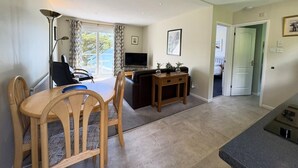 A modern living room with a dining area, a flat-screen TV, and a view of the outdoors. - Cosy Apartment with Private Balcony & Fantastic Sea Views (Torpoint)