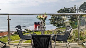 A round table with chairs on a balcony overlooking the sea. - Cornish Duplex 2 Bedroom Apartment with Stunning Sea Views (Torpoint)