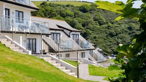 A modern building with multiple levels, a staircase, and a view of a green hillside. - Cornish Duplex 2 Bedroom Apartment with Stunning Sea Views (Torpoint)