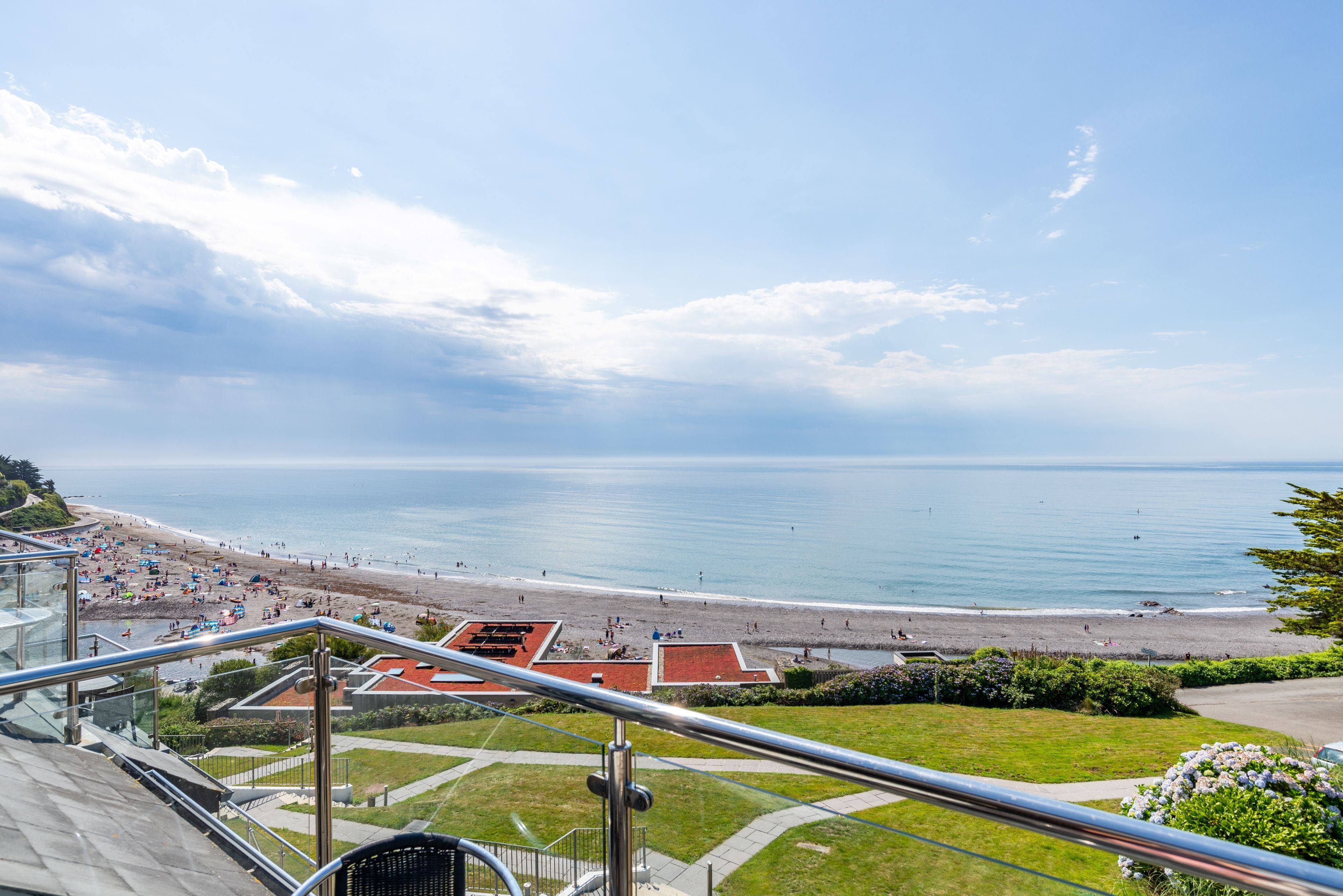 Vista costeira de um ponto alto, com uma praia e céu claro.
