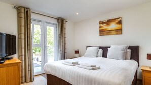 Une chambre d’hôtel avec un lit, une télévision, un tableau et une vue à travers la porte vitrée.
