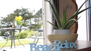 Une table en bois sur laquelle est posée une plante d’aloe vera en pot, ainsi qu’un panneau décoratif sur lequel on peut lire : « Détente à la plage ».