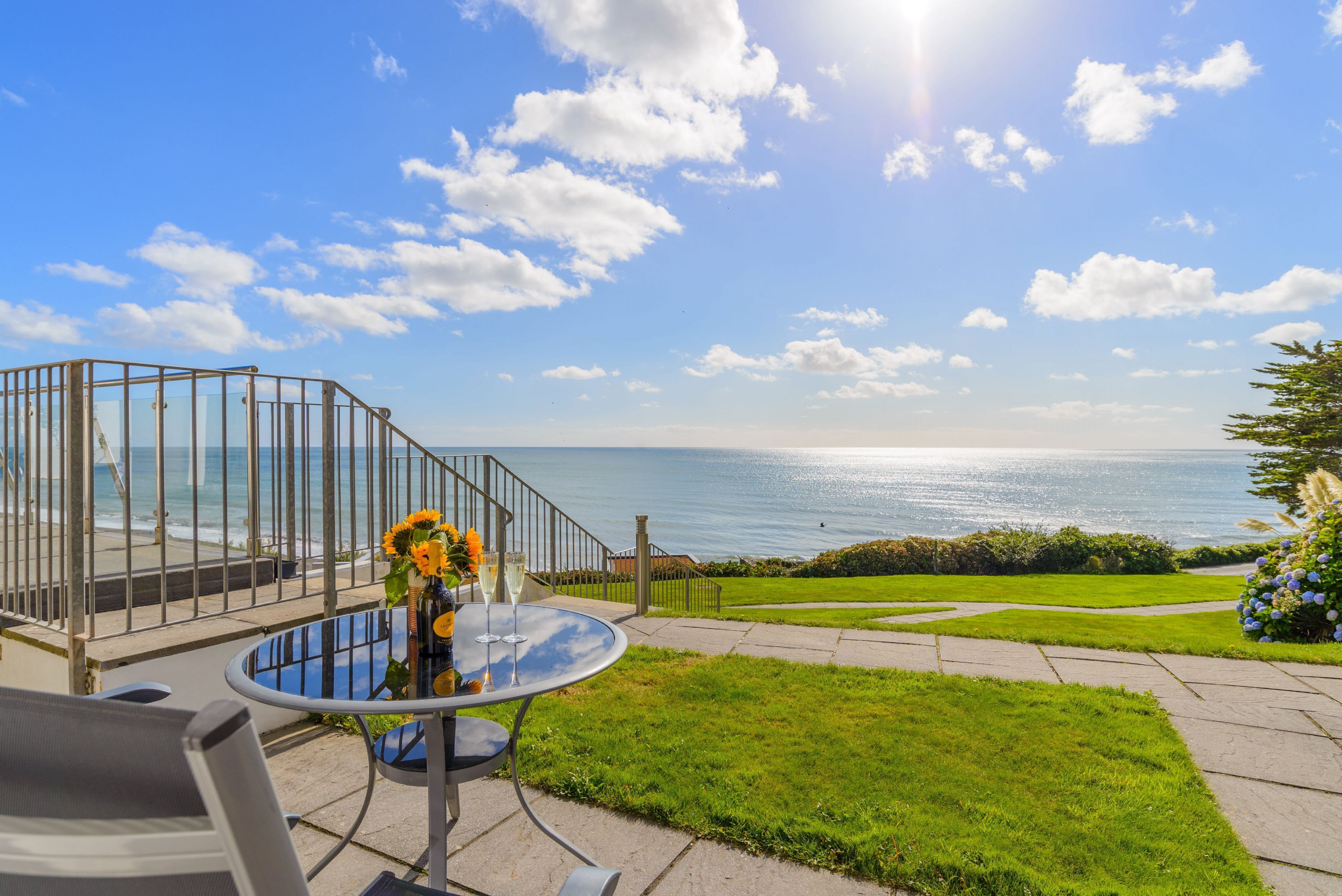 Eine Terrasse mit Glastisch und Stühlen mit Blick auf den Ozean.