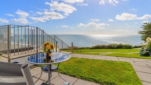 Une terrasse avec une table et des chaises en verre, donnant sur l’océan.