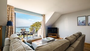 A modern living room with a large window, a sofa, a television, and a small table. - Fantastic Sea Views from this Newly Refurbished Duplex Apartment (Torpoint)