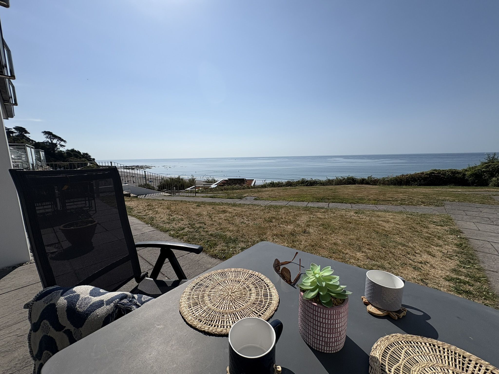 Um pátio com uma mesa posta para dois, com vista para a praia.