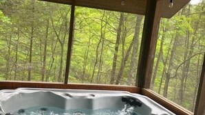 Ein Whirlpool mit Blick auf einen Wald durch große Fenster.