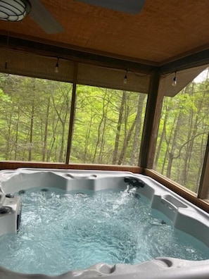 Relax in a hot tub with a serene forest view.