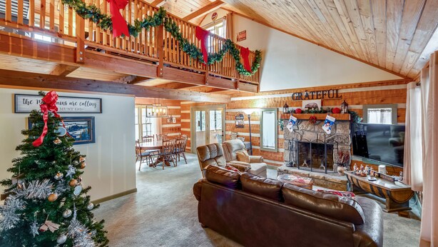 Ein gemütliches Wohnzimmer mit Kamin, Weihnachtstannenbaum und Balkon mit festlicher Dekoration.