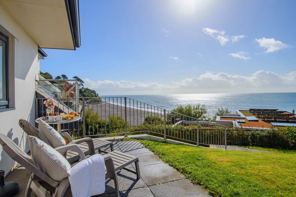 A balcony with a view of the ocean, a table with flowers, and two lounge chairs. - Panoramic Sea Views from this 2 Bedroom Cornish Townhouse (Torpoint)