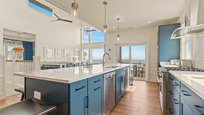 A modern kitchen with a large island, built-in appliances, and a view to the outside.