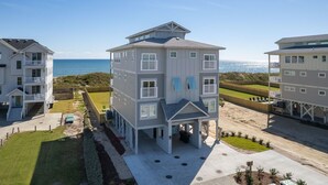 A multi-story beachfront property with a covered patio and a view of the ocean.