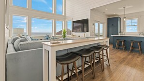 A modern kitchen with a large island, bar stools, and a view of the ocean.