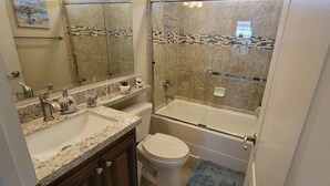 A bathroom with a double sink, a toilet, and a glass-enclosed shower.