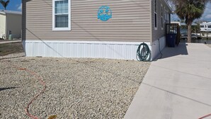 A mobile home with a logo on the side, a window, and a gravel driveway.