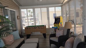 A spacious living area with a pool table, comfortable seating, and large windows.