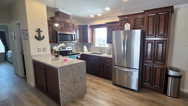 A modern kitchen with dark wood cabinets, stainless steel appliances, granite countertops, and a small island.