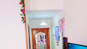 A hallway with a wooden door, a white chair, a desk with a computer monitor, and a mirror. - Altea Royale (Naples)