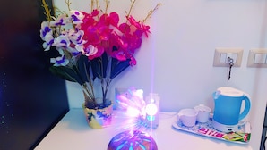 A white table with a vase of flowers, a blue kettle, and a tray with cups and a box of tissues. - Altea Royale (Naples)