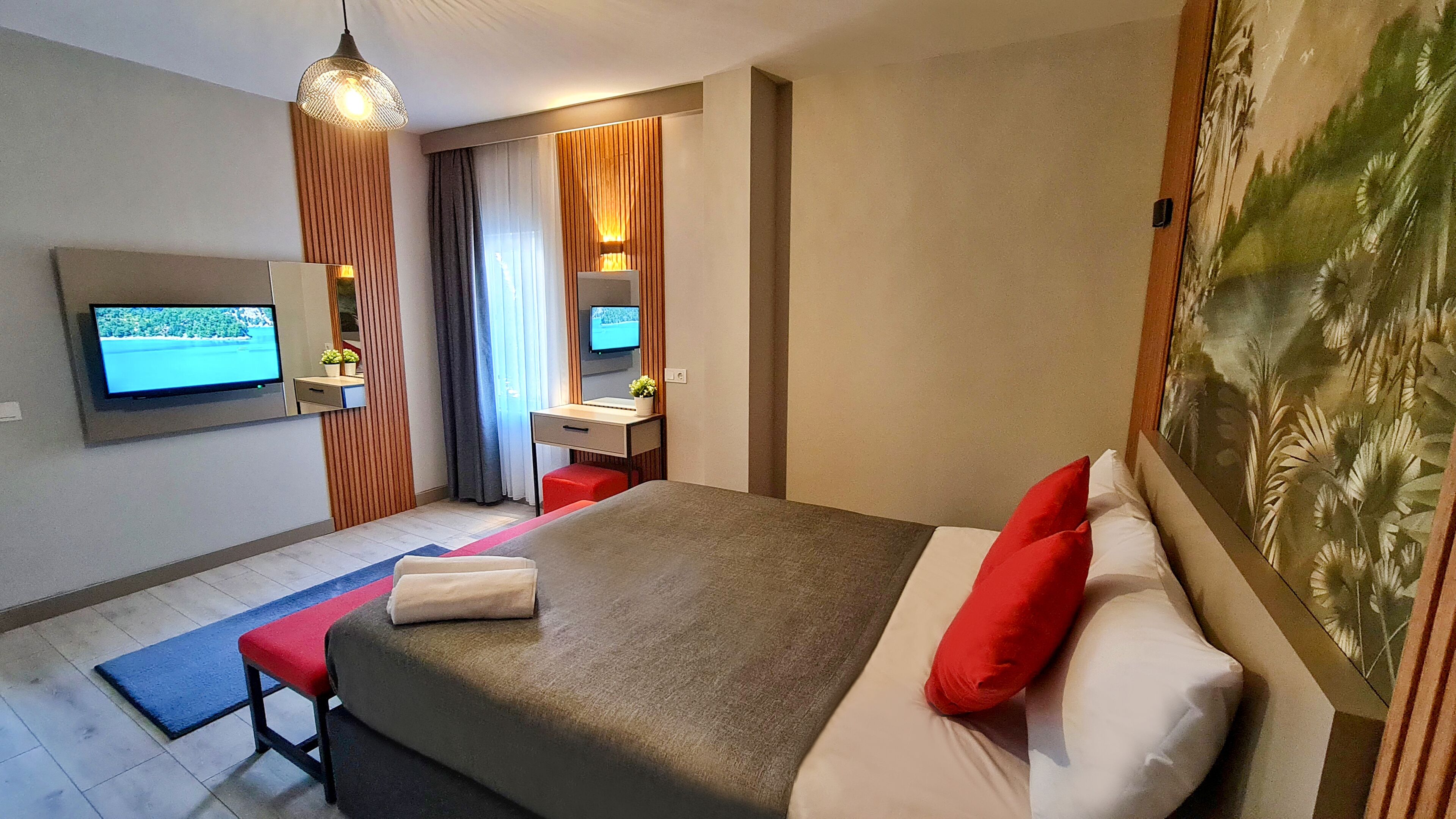 Una habitación de hotel moderna con una cama grande, un escritorio, un televisor y un cuadro en la pared.