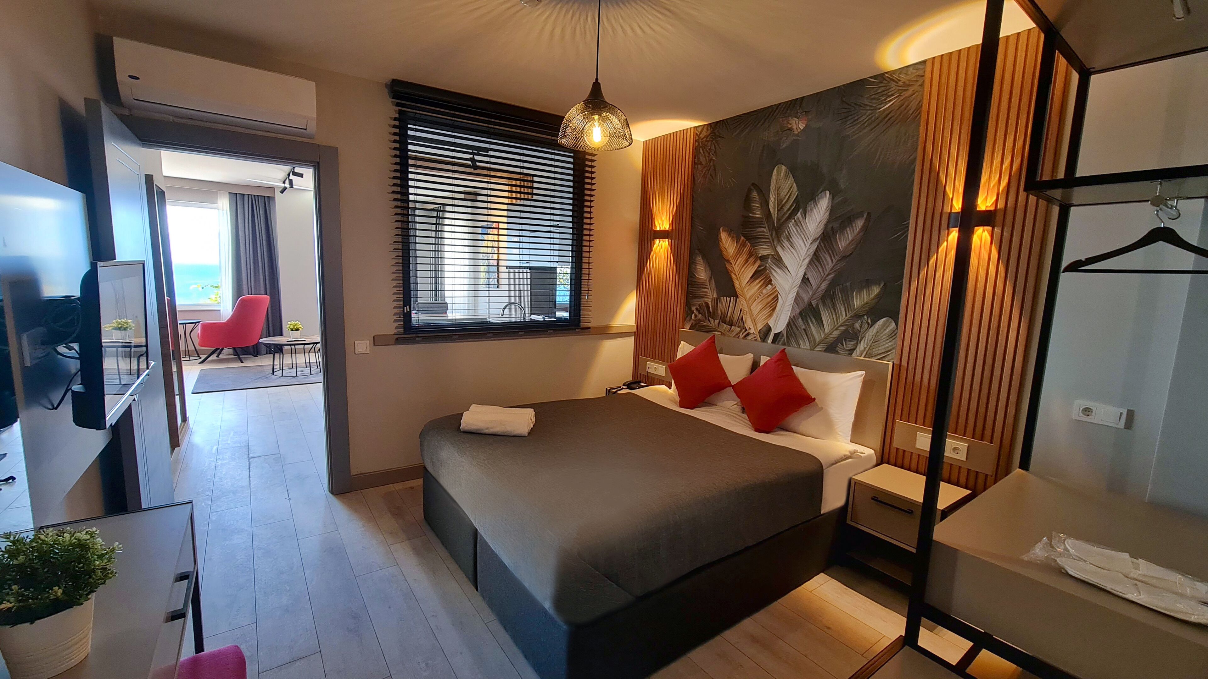 Une chambre d’hôtel moderne, dotée d’un grand lit, d’une télévision, d’un bureau et offrant une vue sur l’extérieur.