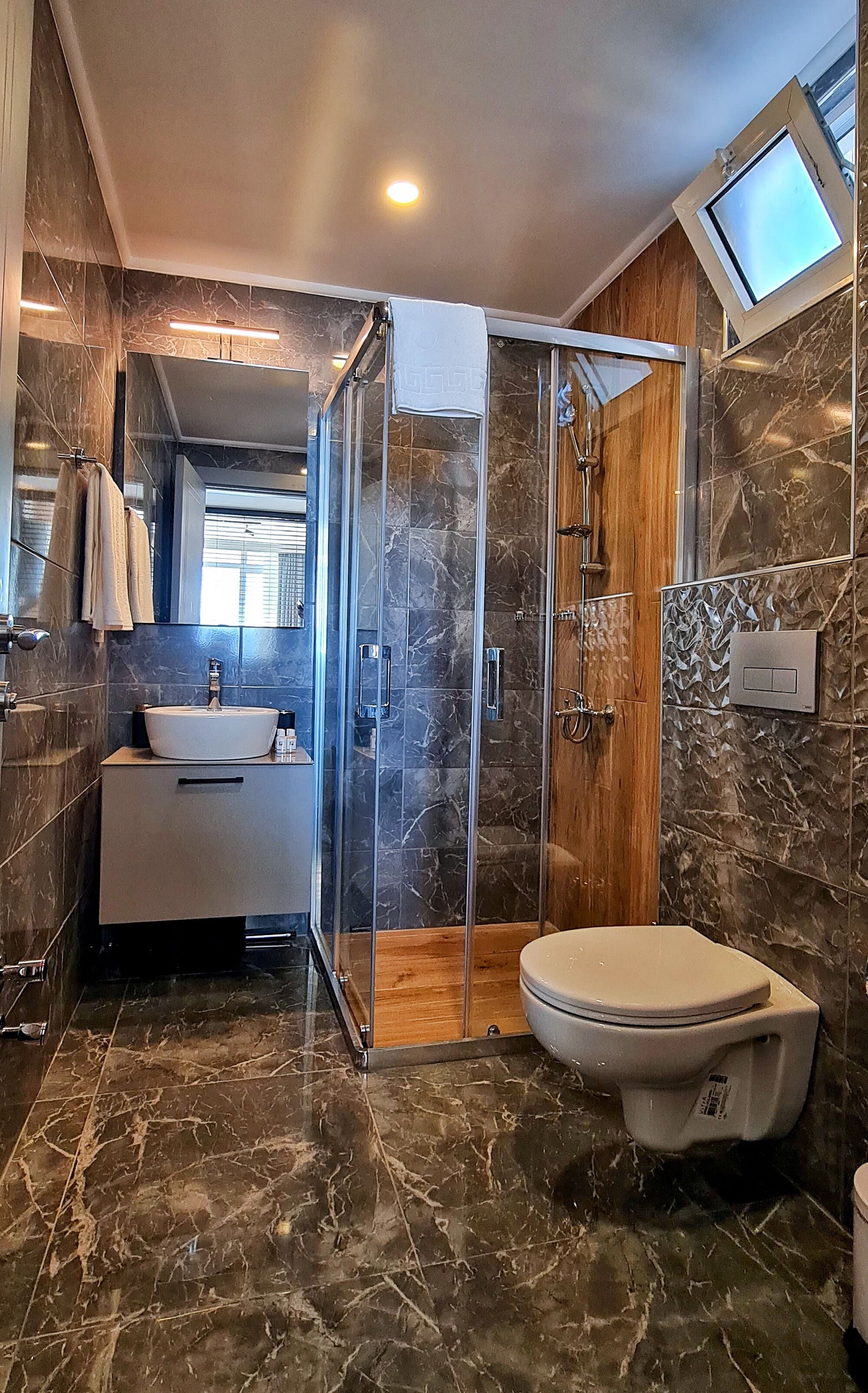 Une salle de bain moderne avec une douche à parois de verre, un lavabo blanc et des toilettes.