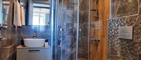 A modern bathroom with a glass-enclosed shower, a white sink, and a toilet.