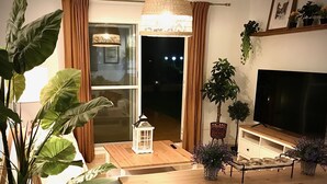A cozy living room with a wooden table, a TV, and various potted plants. - Spectacular apartment with sea views. WIFI. SmartTV 58” (Los Geraneos)