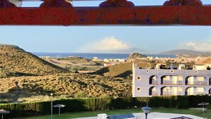A pool area with a view of a coastal town, a hill, and a building with multiple windows. - Spectacular apartment with sea views. WIFI. SmartTV 58” (Los Geraneos)