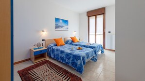 A bedroom with two beds, a nightstand, a rug, and a painting on the wall.