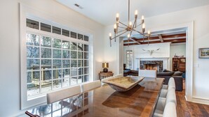 A spacious living room with a large wooden dining table, a chandelier, and a fireplace. - Luxury estate, swim spa, game room, theater, fireplaces, views. (Gatlinburg)