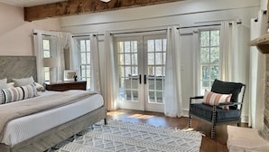 A bedroom with a bed, a chair, a rug, and a view through large glass doors. - Luxury estate, swim spa, game room, theater, fireplaces, views. (Gatlinburg)