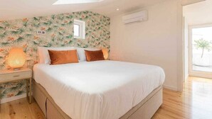 Une chambre à coucher avec un grand lit, une table de chevet, une fenêtre et un luminaire au plafond.