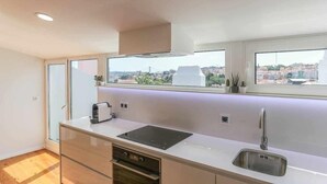 Une cuisine moderne équipée d’une cuisinière intégrée, d’un évier et d’une fenêtre donnant sur un paysage urbain.