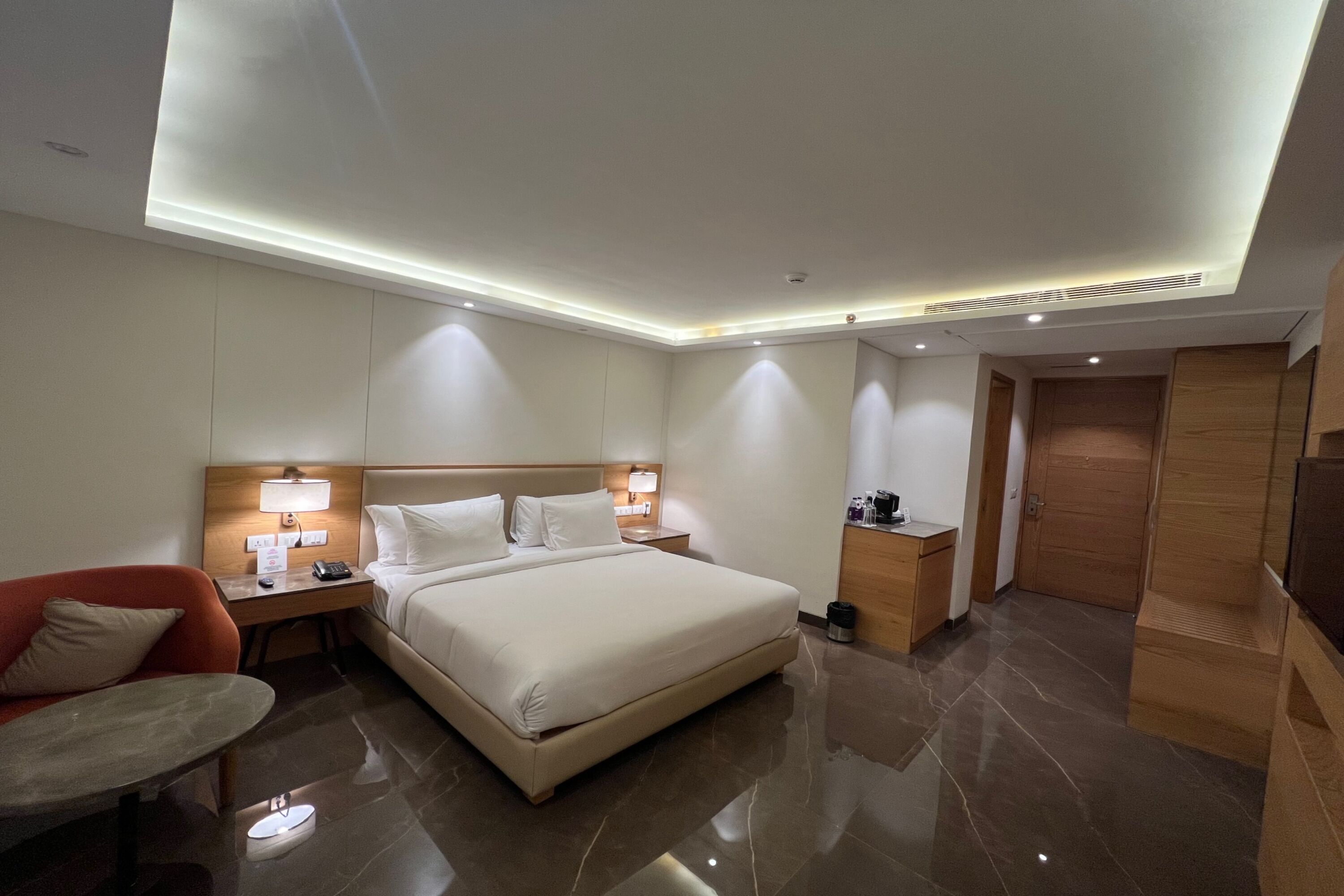 Een hotelkamer met een groot bed, nachtkastjes met lampen, een zithoekje, een houten kledingkast en een televisie.